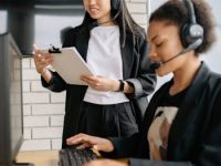 Two women in a call center working with headsets and computers, focusing on customer support.